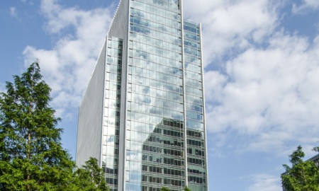 ONDON, UK - JULY 1, 2014: Sunbathers enjoying the greenery of Jubilee Park in London's Docklands overlooked by the gleaming headquarters of international law group Clifford Chance.